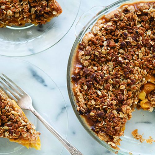 Sliced peach pie with serving plates